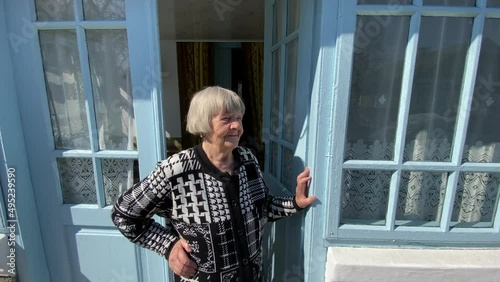 An elderly woman stands on the porch of a rural house in Ternopil region, Ukraine