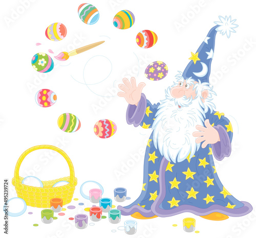 Old wizard with a big white beard coloring and decorating Easter gift eggs with a magic flying paintbrush and bright paints, vector cartoon illustration isolated on a white background