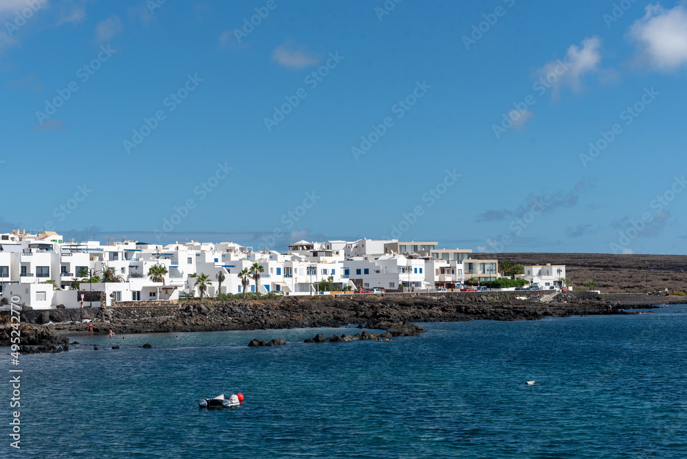 casas blancas en Punta Mujeres en Lanzarote en las Islas Canarias. Costa canaria con barcos, mar turquesas y casas al fondo. Paisaje y naturaleza de España. 