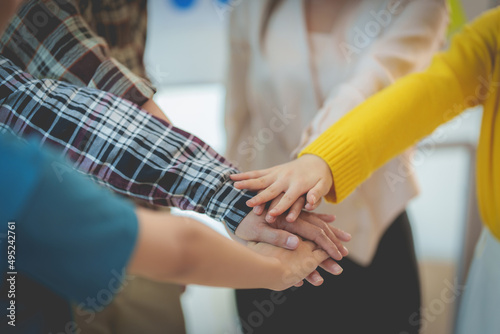 Group of Multiracial people putting their hands working together showing oneness symbol.