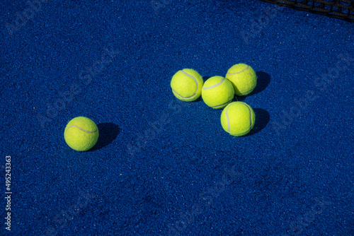 selective focus, five paddle tennis balls and the net of a blue paddle tennis court © VicVaz