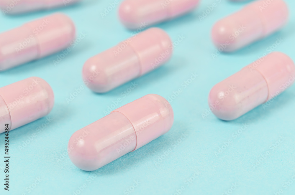 Pink capsule pills on blue background. Pink capsule pills on blue background.