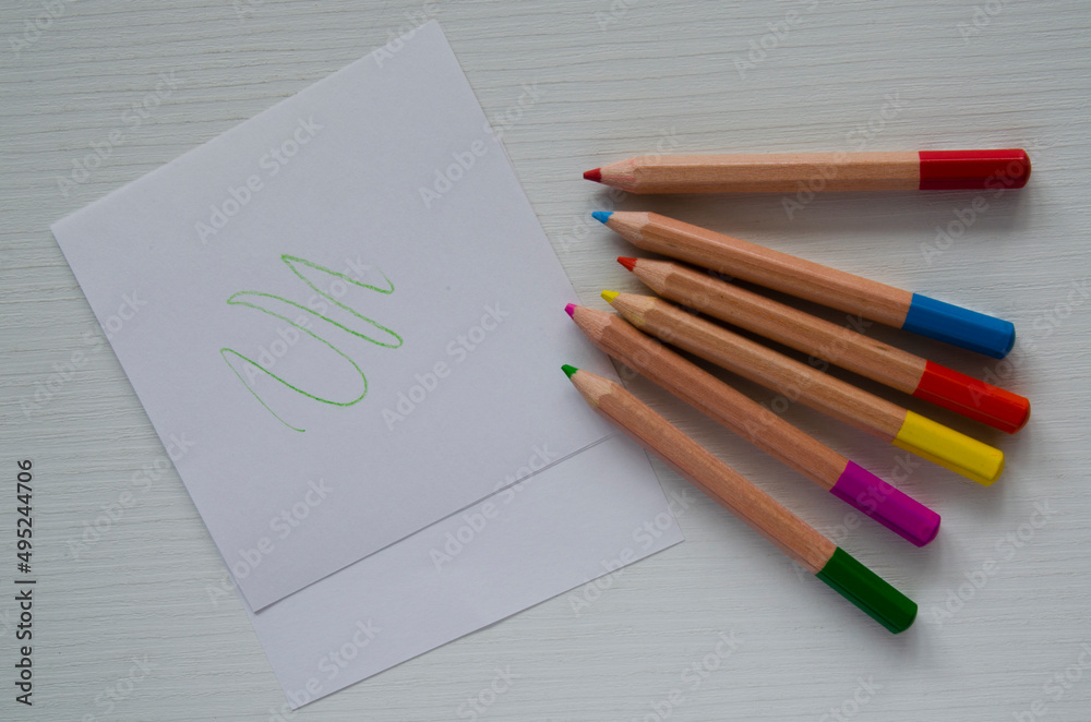 Small colored pencils and sheets of white paper on the table, top view. A template, a place for drawing,writing,sketches. Small colored pencils and sheets of white paper on the table, top view. A template, a place for drawing,writing,sketches.