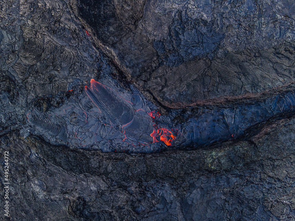 Landscape of Iceland after volcanic eruption. View of lava flow on Reykjanes Peninsula. partially red lava flow and liquid magma. Dark structures of old cooled lava Landscape of Iceland after volcanic eruption. View of lava flow on Reykjanes Peninsula. partially red lava flow and liquid magma. Dark structures of old cooled lava