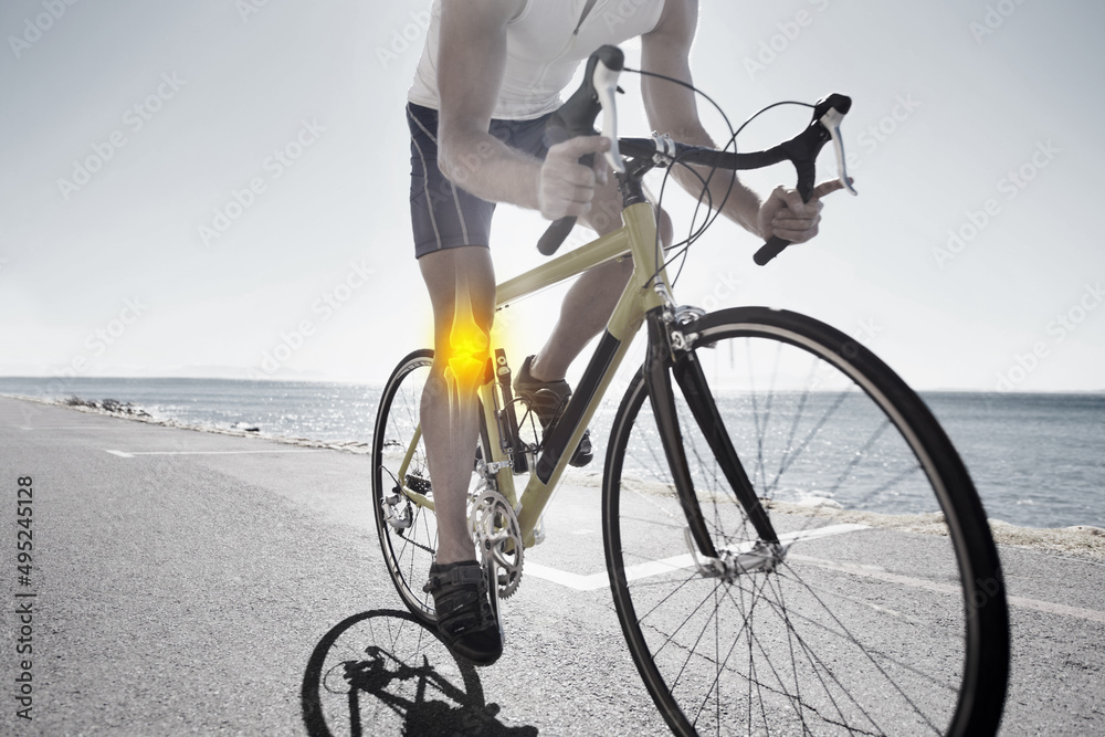 Ride through the pain. Cropped view of a cyclist with knee issues cycling along an ocean road. Ride through the pain. Cropped view of a cyclist with knee issues cycling along an ocean road.