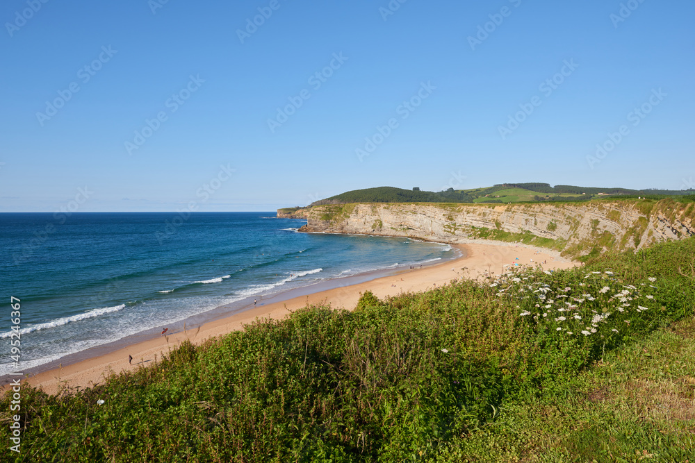 A beach surrounded by greenery and blue skies in northern Spain