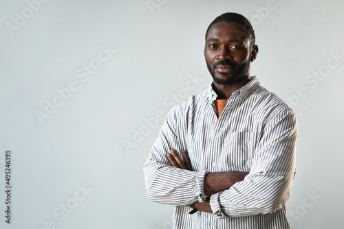 Minimal waist up portrait of successful African American businessman standing with arms crossed against white background, copy space
