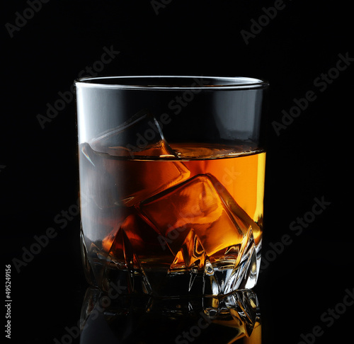 Scotch whiskey in an elegant glass with ice cubes on black background.