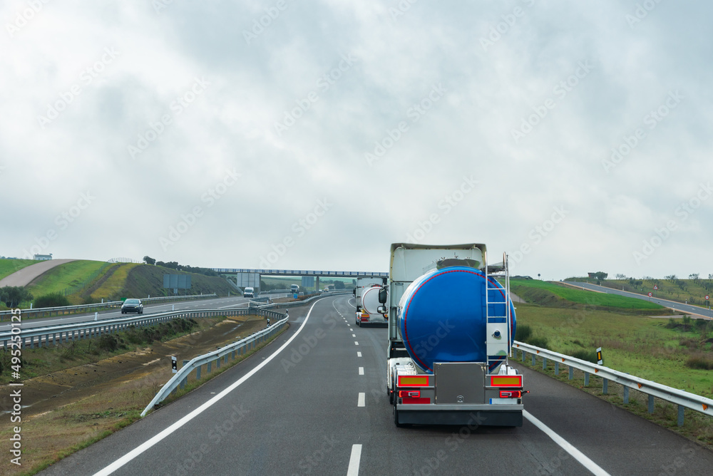 Two tank trucks for the transport of food liquids circulating on the highway.