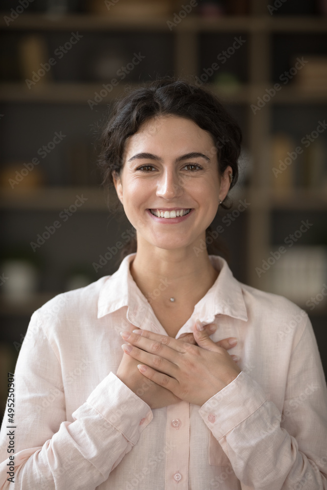 Happy grateful millennial Hispanic girl applying hands to chest in gesture of thank, gratitude. Young woman making sign of kindness, showing symbol of love, care, support. Vertical shot Happy grateful millennial Hispanic girl applying hands to chest in gesture of thank, gratitude. Young woman making sign of kindness, showing symbol of love, care, support. Vertical shot