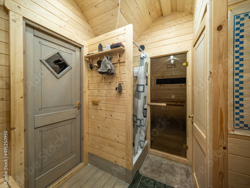 Wooden interior of modern bathhouse. Shower and door to sauna.
