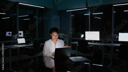 African-American businesswoman having video conference on laptop working late in dark empty office