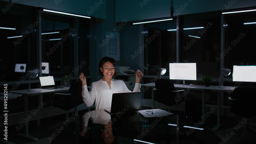 African-American businesswoman raise fists and celebrate business success working late