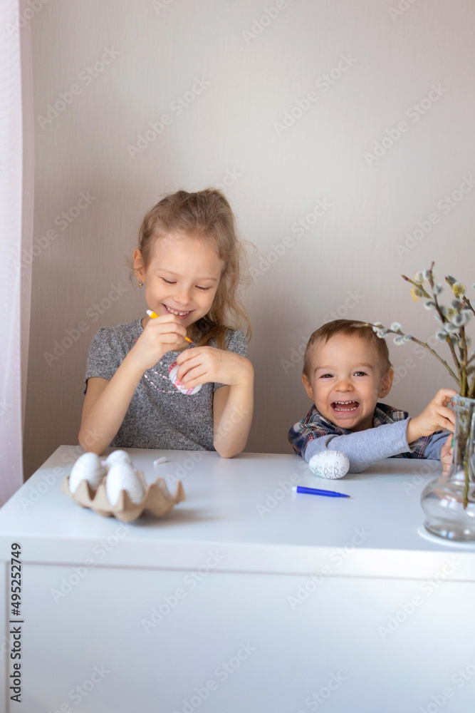 Brother and sister paint decorative Easter eggs with felt-tip pens Brother and sister paint decorative Easter eggs with felt-tip pens