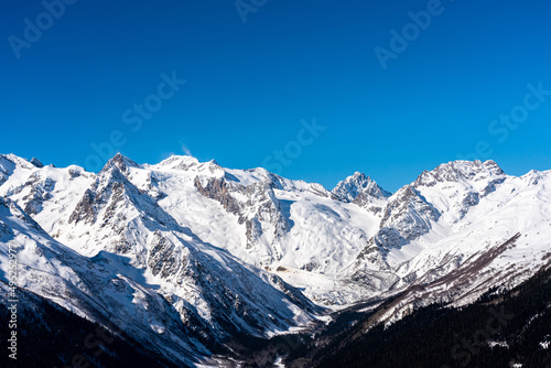 Panoramic view of winter snowy mountains in Caucasus region in Russia with blue sky