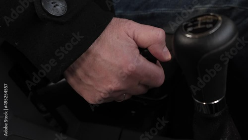 man's hand pulls the handbrake on a car