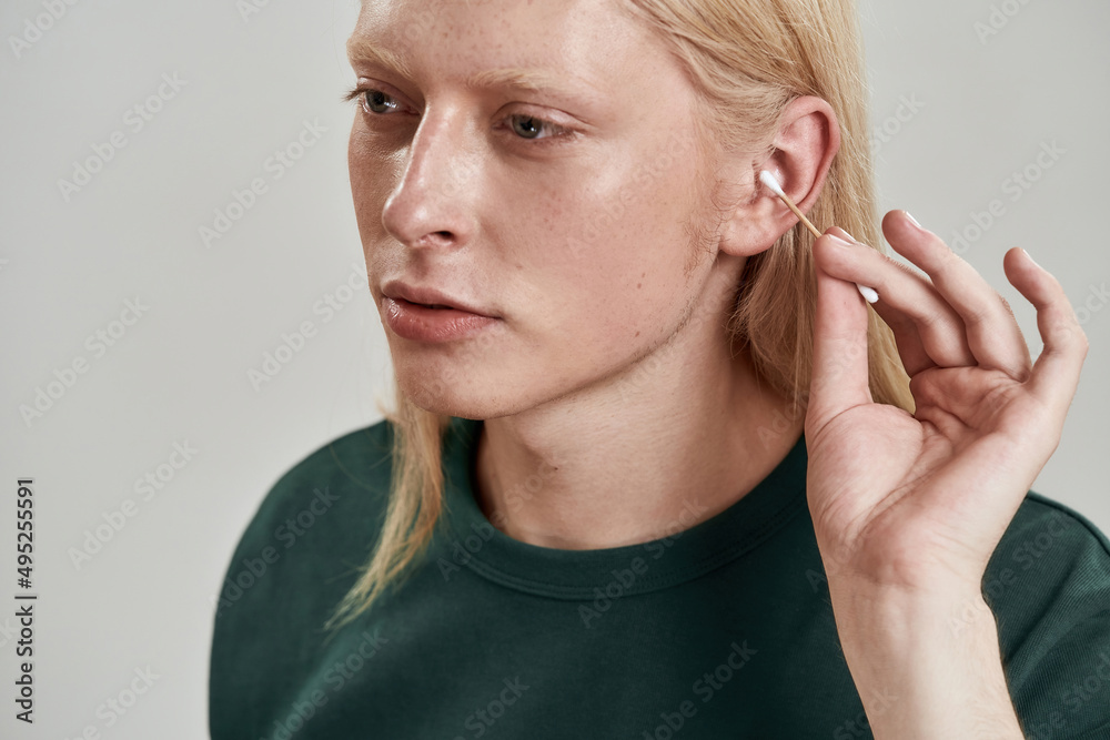 Partial image of guy cleaning ear with ear stick Partial image of guy cleaning ear with ear stick