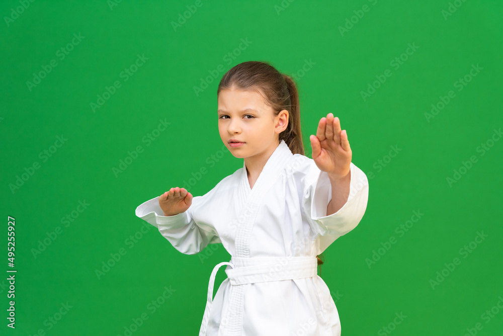 A child in a white kimono, martial arts from an early age, children's discipline, a karate girl on a green background, competitions in martial arts.