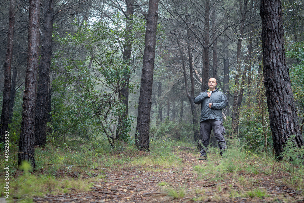 Hiker man warming up in a cold and wet forest.