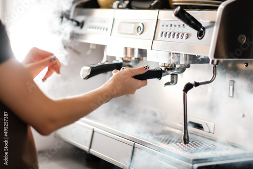 Barista prepares cappuccino using a coffee machine.