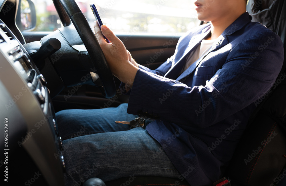 Man sitting in car using mobile phone to text while driving. Close-up of businessman while driving typing message on mobile phone.
