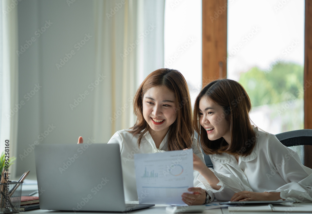 Two asian female colleagues sitting next to each other in an office, business meeting discussion concept.