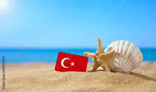 Fototapeta Naklejka Na Ścianę i Meble -  Tropical beach with seashells and Turkey flag. The concept of a paradise vacation on the beaches of Turkey.