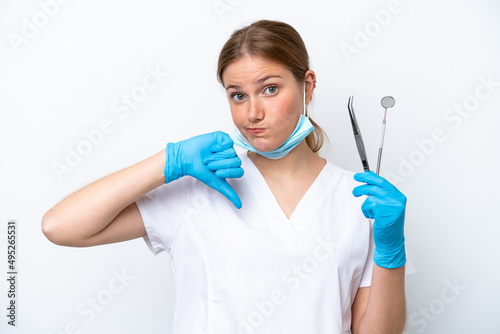 Dentist caucasian woman holding tools isolated on white background showing thumb down with negative expression