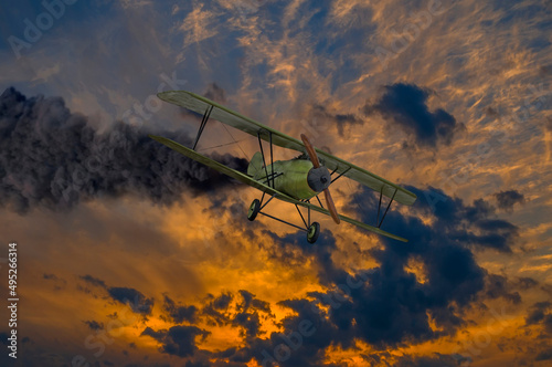 Historic vintage biplane propeller with engine on fire and smoke before crash in dramatic sunset sky. Military reconnaissance aircraft of World war time