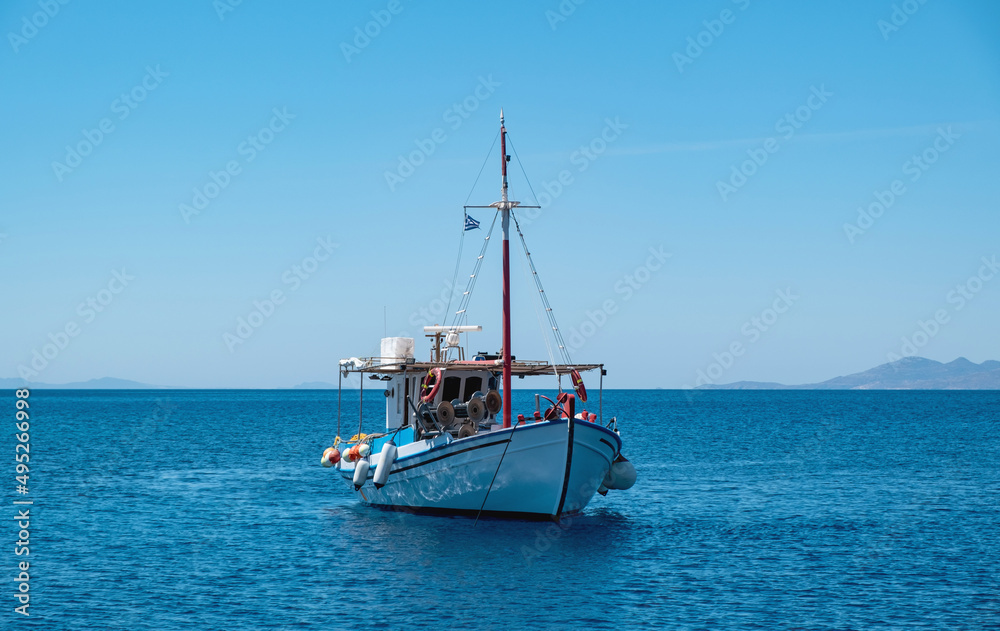 Wooden fishing boat moored in Aegean sea, blue sky background. Koufonisi Greek island, Cyclades.