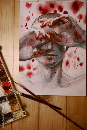 The photo shows a drawing. A man closes his eyes with his hands on the hands of the blood around the blood stain. War.