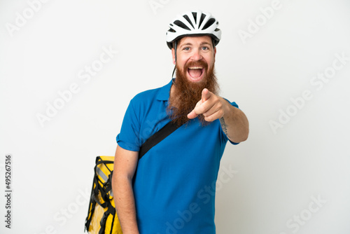 Young reddish caucasian man with thermal backpack isolate don white background surprised and pointing front
