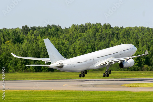 Passenger airplane take off against the background of a green forest on a runway.