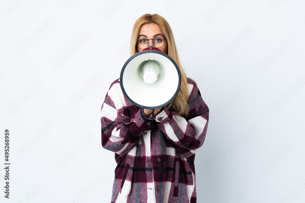 Obraz premium Young Uruguayan blonde woman over isolated white background shouting through a megaphone