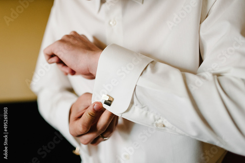 Hand's groom wears a metallic silver cufflinks stud. Wedding morning.