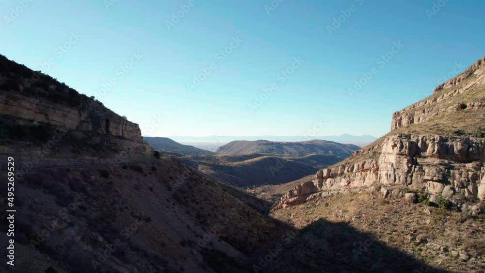 Drone aerial view panning to the right of a large valley with cliffs Drone aerial view panning to the right of a large valley with cliffs