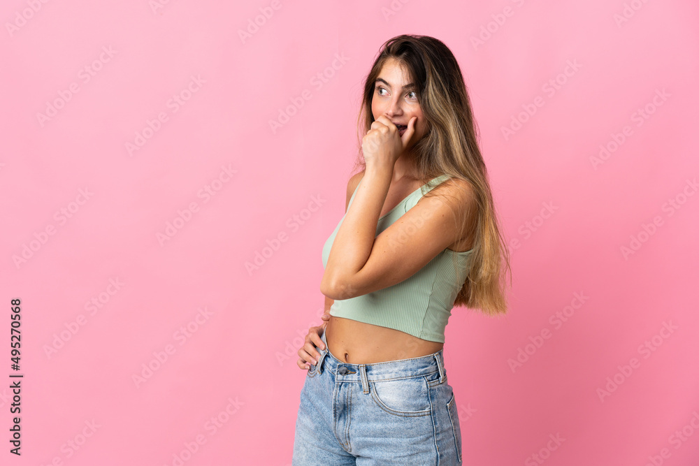 Young caucasian woman isolated on pink background doing surprise gesture while looking to the side Young caucasian woman isolated on pink background doing surprise gesture while looking to the side