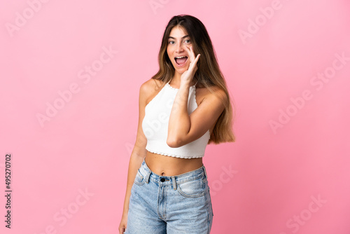 Young caucasian woman isolated on pink background shouting with mouth wide open