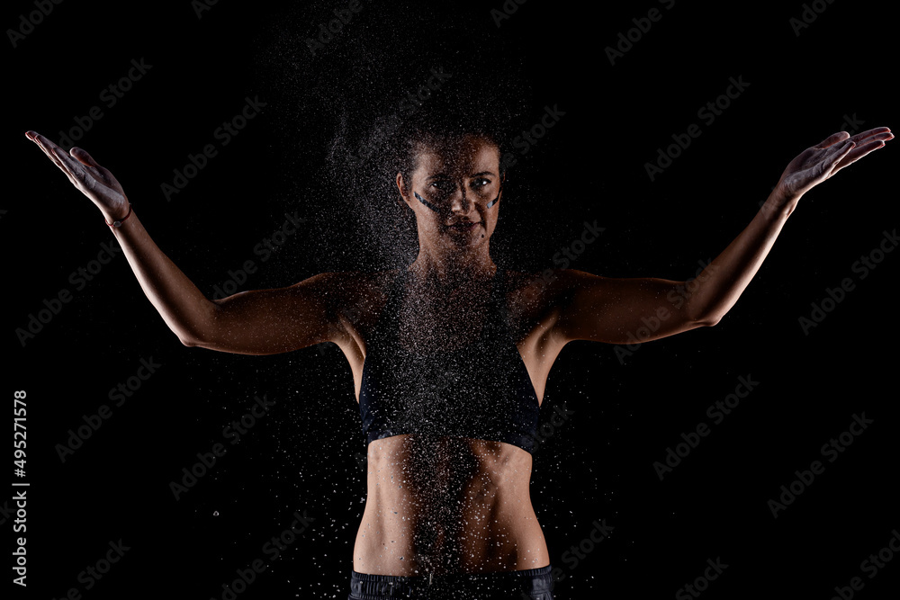 Obraz premium Kickboxer kirl with magnesium powder on her hands punching with dust visible..