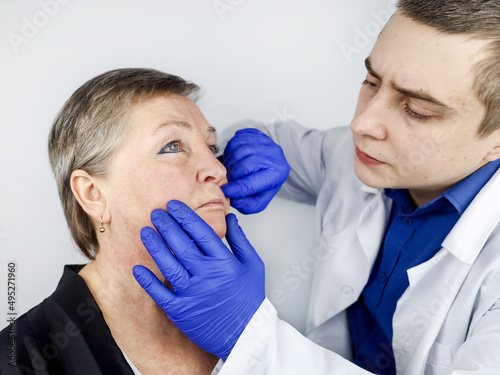 An elderly woman at a plastic surgeon's consultation regarding the elimination of age-related wrinkles. Gubo-chin folds, lowered corners of the mouth. Correction of the lower third of the face.