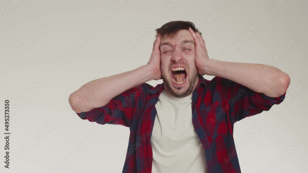Man grabs head with both hands and screams from headache, earache ...