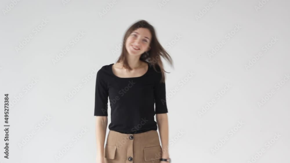 A beautiful cheerful young girl is dancing on an isolated white background in the studio. The concept of people's lifestyle. Dancing shaking her head with her hair flying A beautiful cheerful young girl is dancing on an isolated white background in the studio. The concept of people's lifestyle. Dancing shaking her head with her hair flying