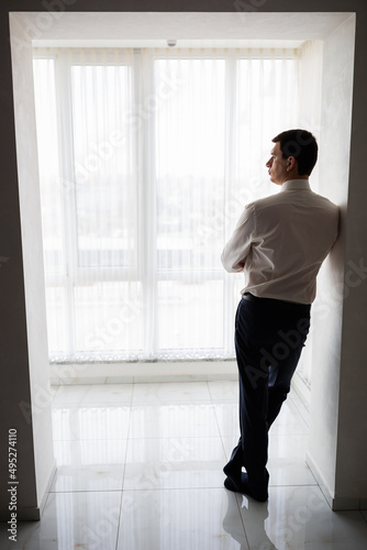 A respectable businessman in a hotel room, standing near the window. Groom's fees