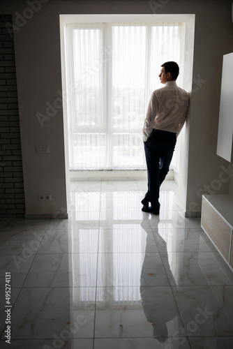 A respectable businessman in a hotel room, standing near the window. Groom's fees