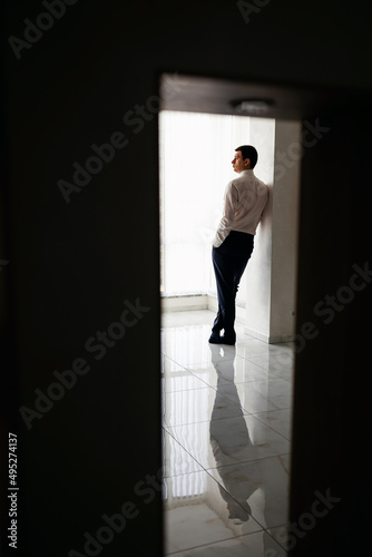 A respectable businessman in a hotel room  standing near the window. Groom s fees