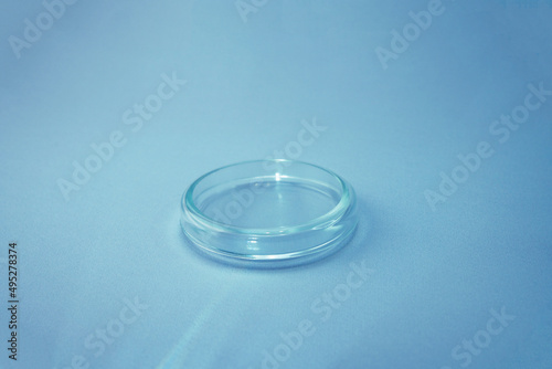 Empty glass plate petri.Petri dish for biological research.Isolated on blue background. Laboratory tests and research.Chemistry science or medical biology experiment.Growing colonies in a petri dish