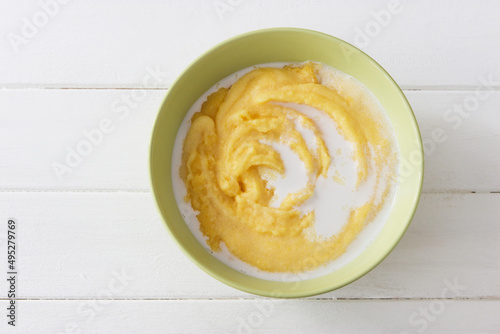 Yellow sweet polenta with coconut milk on white background.