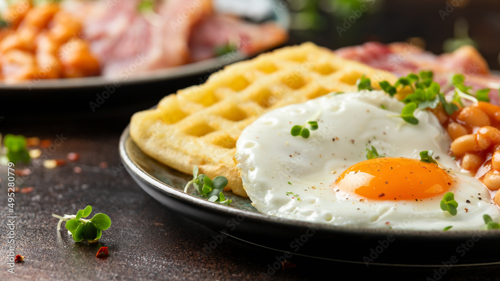 Potato waffles with fried egg, bacon and baked beans. Morning breakfast Potato waffles with fried egg, bacon and baked beans. Morning breakfast