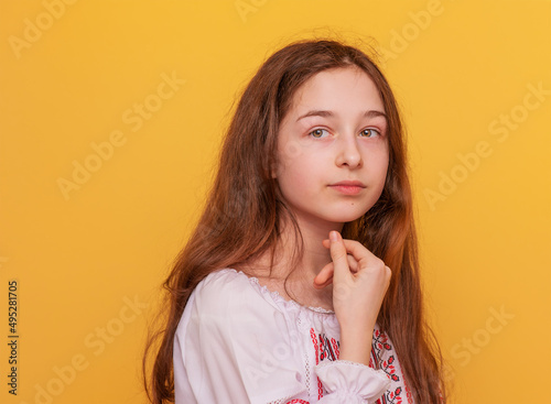 Girl on a yellow background. Portrait of an 11-year-old girl in Ukrainian embroidered clothes.