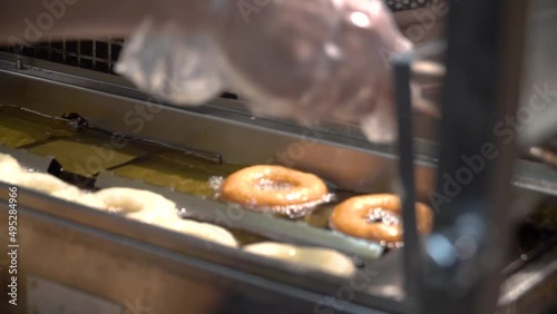 On the assembly line, donuts are fried in oil. They float in an oil vat. photo